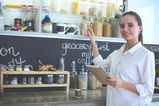 Young woman using a tablet computer to cook in her kitchen .