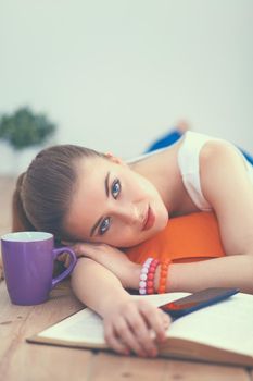 Smiling young woman lying on a white floor with pillow.