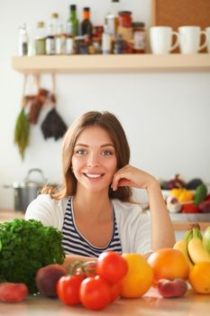 Young woman standing near desk in the kitchen.