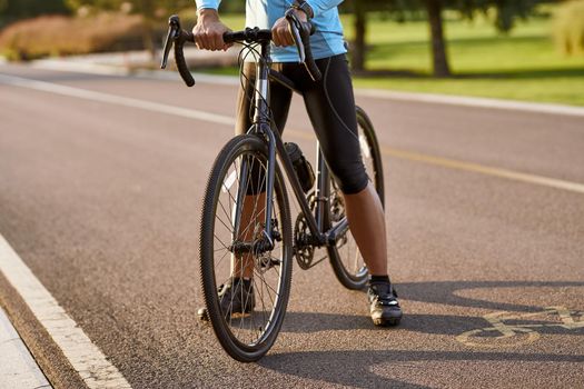 Cycling outdoors. Cropped shot of a man in sportswear standing with his road mountain bike on the road in park. Active lifestyle and sport