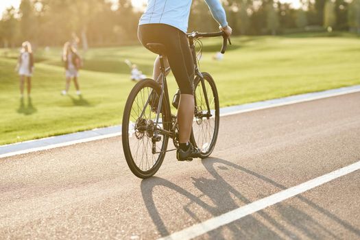 Cropped shot of a man riding mountain bike in park during sunset, cycling outdoors on a summer day. Active lifestyle concept