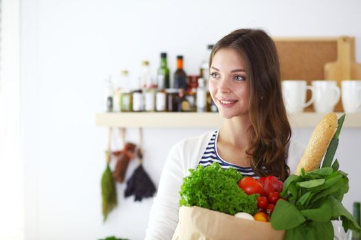 Young woman holding grocery shopping bag with vegetables .Standing in the kitchen. Young woman.