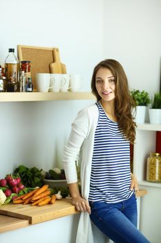 Young woman standing near desk in the kitchen.