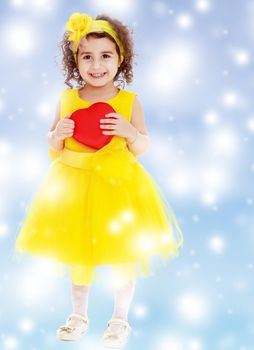 Adorable little girl in bright yellow elegant dress. Close to her heart.Blue winter background with white snowflakes.