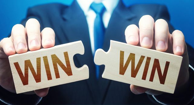 Man holding two puzzles with Win-Win words. A negotiation strategy makes all parties succeed. Mutual benefit and good contract terms. Compromise, perfect. Consent and satisfaction. Trade and diplomacy