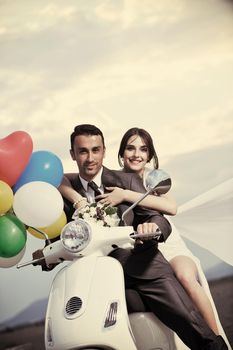 wedding sce of bride and groom just married couple on the beach ride white scooter and have fun