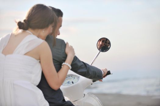 wedding sce of bride and groom just married couple on the beach ride white scooter and have fun