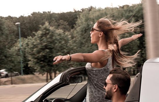 happy young woman standing in convertible car.city life