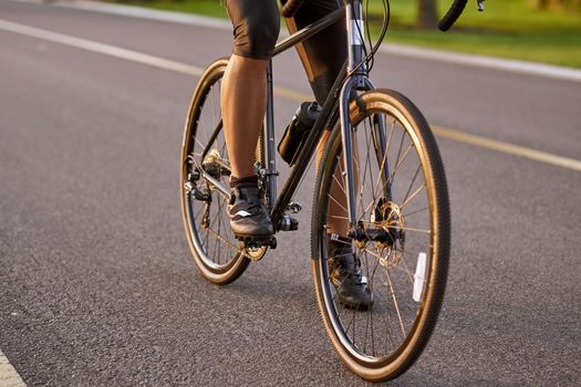 Riding. Cropped shot of a man cycling outdoors. Focus on male legs. Active lifestyle and sport concept