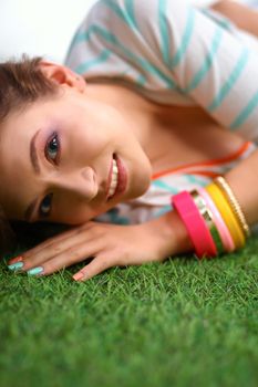 Beautiful young woman lying on the green grass.