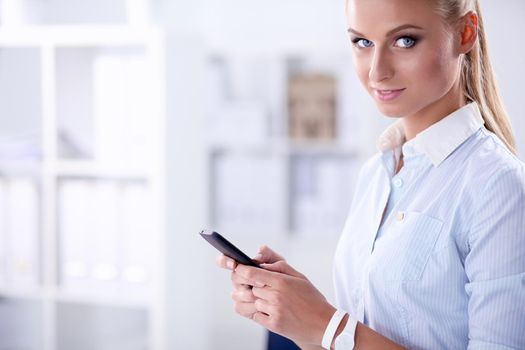 Businesswoman sending message with smartphone in office.