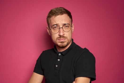 man in a black shirt wearing glasses emotions pink background. High quality photo