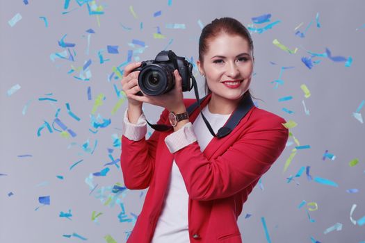 Beautiful happy woman with camera at celebration party with confetti . Birthday or New Year eve celebrating concept.