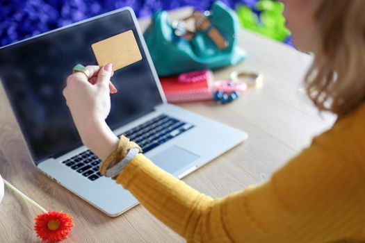 Young woman holding credit card and using laptop computer. Online shopping concept.