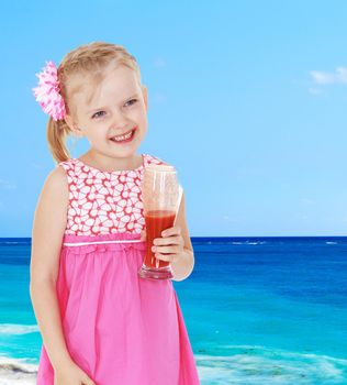 Smiling little girl with a glass of juice on a sea background.
