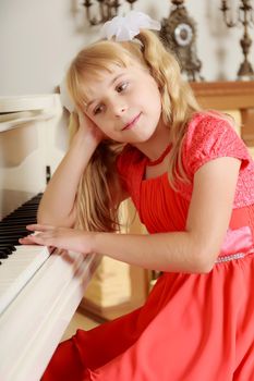 Sad little girl in a long orange dress,with long blonde hair braided in pigtails . Close-up