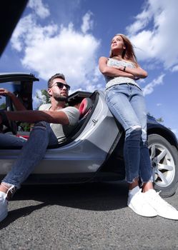 bottom view.serious young couple standing near the car. the concept of lifestyle