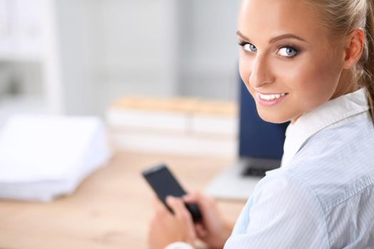 Businesswoman sending message with smartphone in office