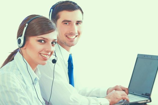 Young business woman and handsome businessman in headsets using laptops while working in office.