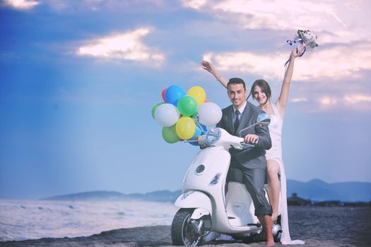 wedding sce of bride and groom just married couple on the beach ride white scooter and have fun