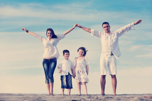 happy young family have fun on beachand showing home sign with conncected hands while protecting childrens