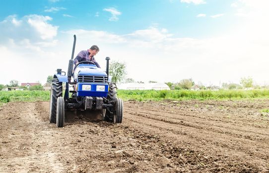 Farmer is processing soil on a tractor. Soil milling, crumbling mixing. Loosening surface, cultivating land for further planting. Agroindustry, farming. Agriculture, growing organic food vegetables