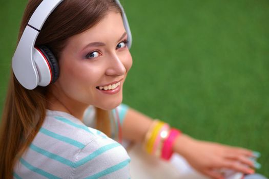 Woman listening to the music sitting on grass.