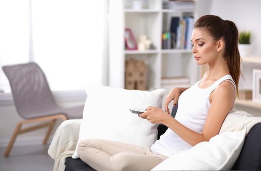 Portrait of young woman watching TV at home.