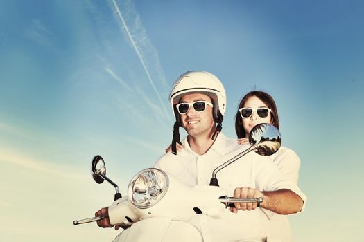 Portrait of happy young love couple on scooter enjoying themselves in a park at summer time