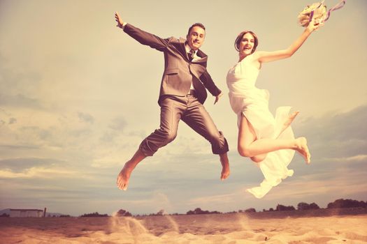 happy just married young couple celebrating and have fun at beautiful beach sunset