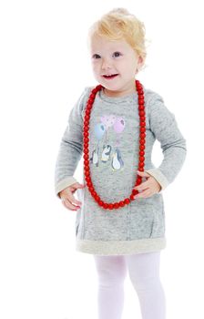 smiling little girl put on her red beads on a white background