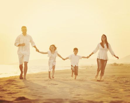 happy young family have fun on beach run and jump  at sunset