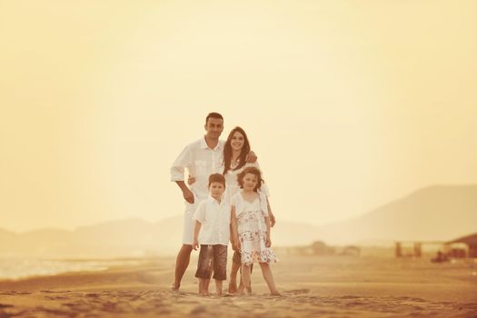 happy young family have fun on beach run and jump  at sunset