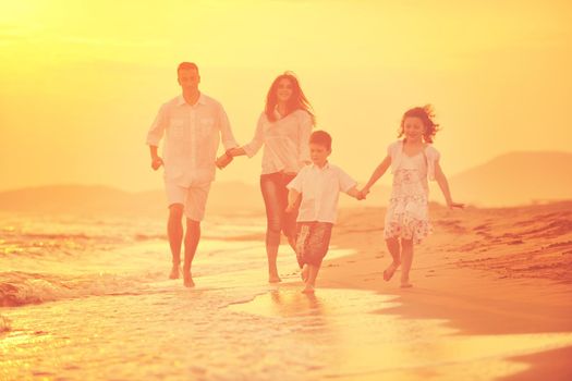 happy young family have fun on beach run and jump  at sunset