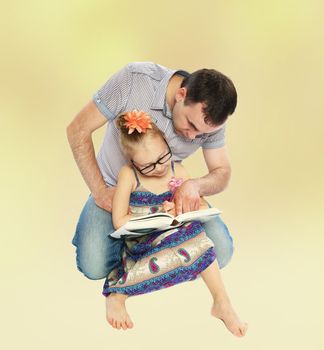 Positive young dad reading a book with her daughter.