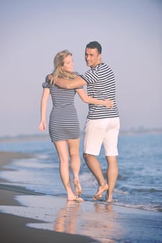 happy young couple have romantic time on beach at sunset