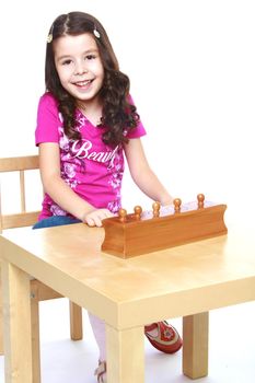 smiling little girl sitting at the table and working with Montessori materials, isolated on a white background.Isolated on white background.