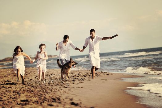 happy young family in white clothing have fun and play with beautiful dog at vacations on beautiful beach 