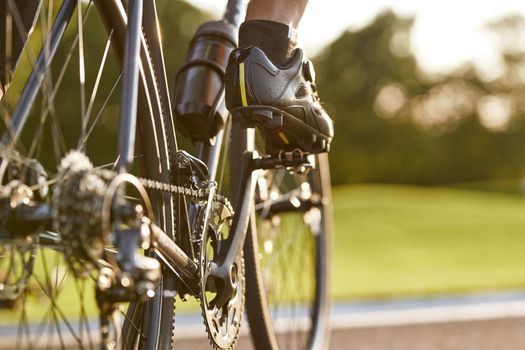 Cropped shot of a man cycling outdoors, focus on male legs. Active lifestyle and sport concept