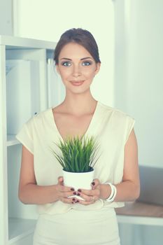 Beautiful woman holding pot with a plant .