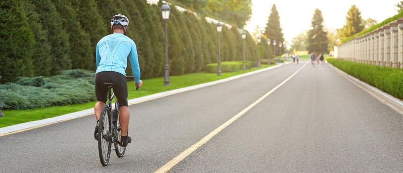 Cropped shot of a man riding mountain bike in park during sunset, cycling outdoors on a summer day. Active lifestyle concept