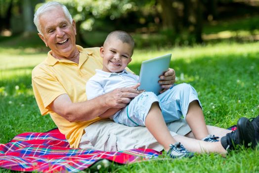 grandfather and child using tablet computer in park