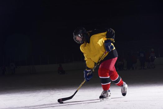 teen girl children ice hockey player in action kicking puck with stick