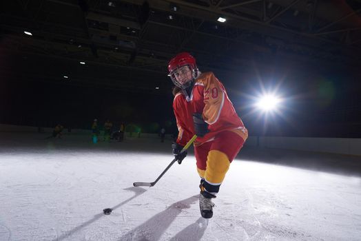 teen girl children ice hockey player in action kicking puck with stick