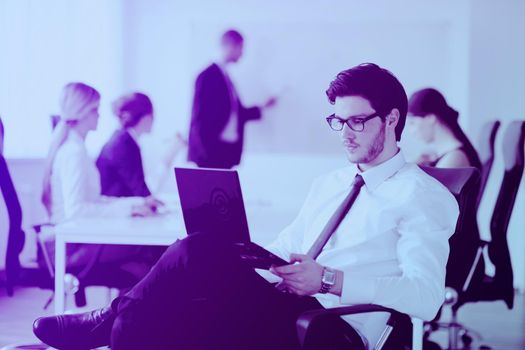 Portrait of a handsome young business man with people  in background at office meeting