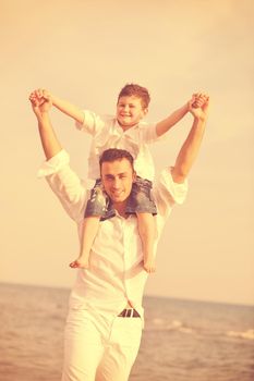 happy young  father and son have fun and enjoy time on beach at sunset and representing healthy family and support concept