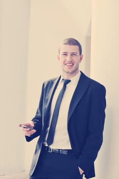 young business man talk by cellphone over bright window in big hall