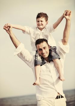 happy young  father and son have fun and enjoy time on beach at sunset and representing healthy family and support concept