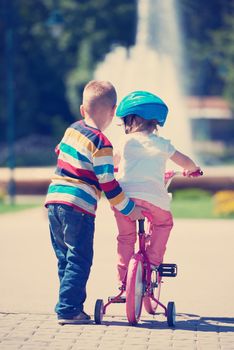 Happy childrens outdoor,  brother and sister in park have fun. Boy and girl in park learning to ride a bike.