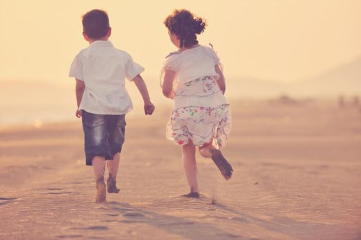 happy young family have fun on beach run and jump  at sunset